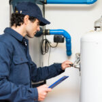A plumber inspects a water heater to determine the source of noises.